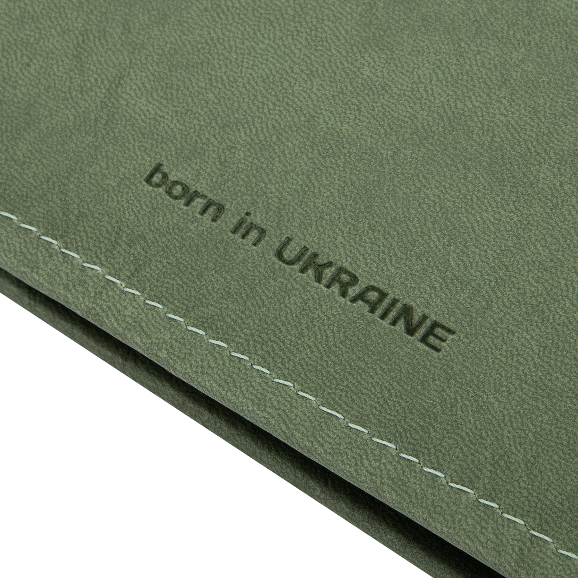 Тиснений напис "born in UKRAINE" на зеленій шкірі.